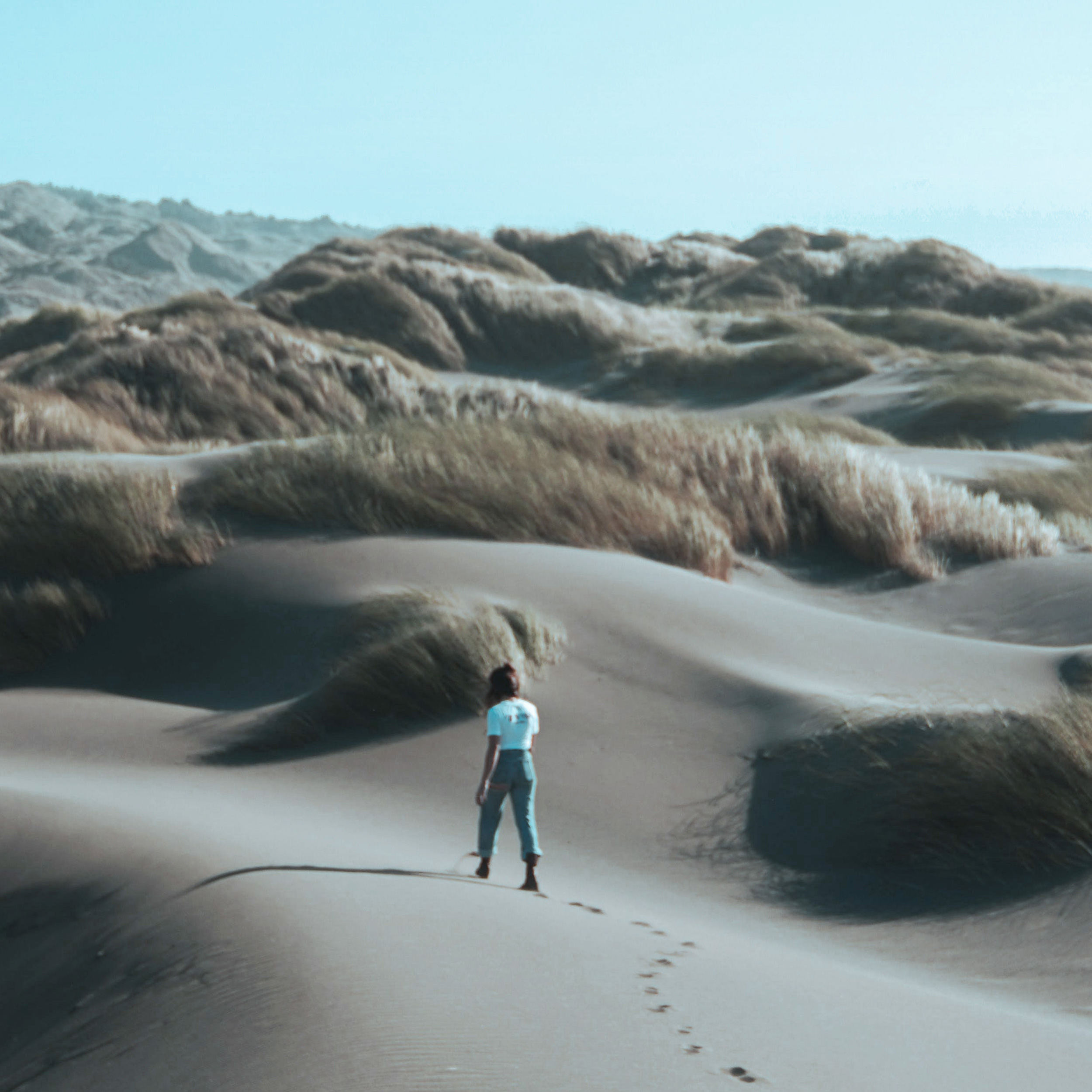 Eine Frau läuft alleine durch eine Dünenlandschaft. © Brady Knoll via pexels.com